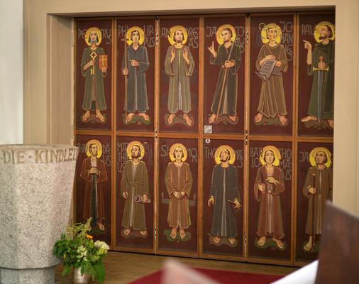 Wand mit versteckter Türe und Bild der zwölf Apostel. Links der Taufstein